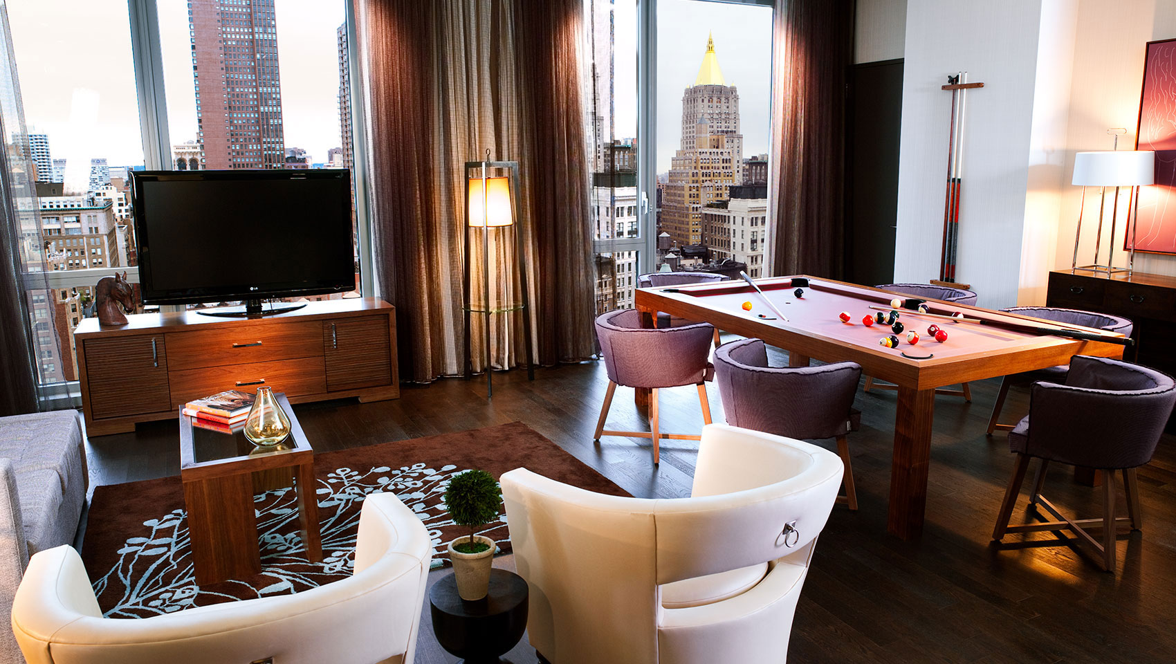 Kimpton Hotel Eventi suite living area with pool table and surrounding seating and views of city buildings